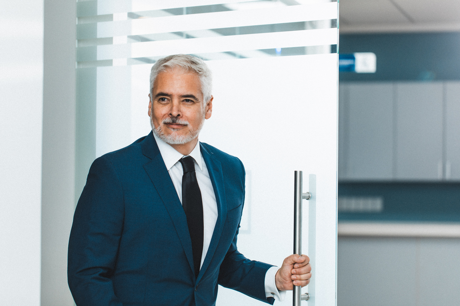 Editorial headshot of Dr. Ariel Ortiz® in a navy suit and tie at the entrance of the Obesity Control Center®.